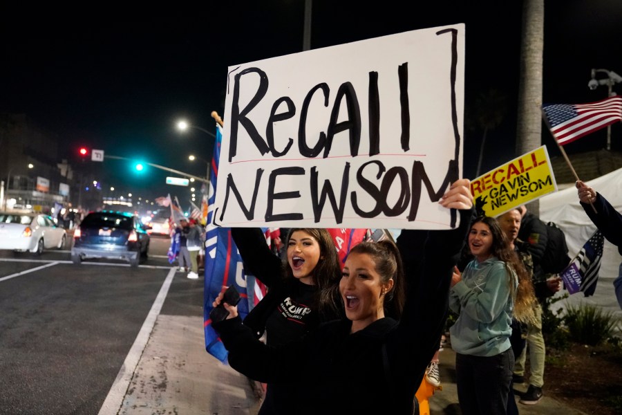 In this Saturday, Nov. 21, 2020, file photo, demonstrators shout slogans while carrying a sign calling for a recall on Gov. Gavin Newsom during a protest against a stay-at-home order amid the COVID-19 pandemic in Huntington Beach. (AP Photo/Marcio Jose Sanchez, File)