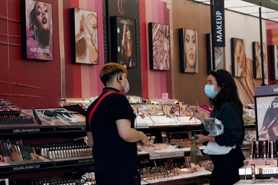 A worker, at left, tends to a customer at a cosmetics shop amid the COVID-19 pandemic Thursday, May 20, 2021, in Los Angeles. (AP Photo/Marcio Jose Sanchez)