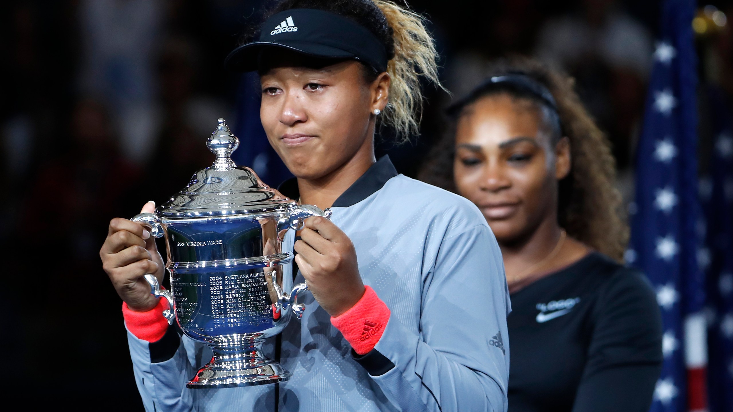 Naomi Osaka, of Japan, holds the trophy after defeating Serena Williams, rear, in the women's final of the U.S. Open tennis tournament in New York on Sept. 8, 2018. (Adam Hunger/Associated Press)