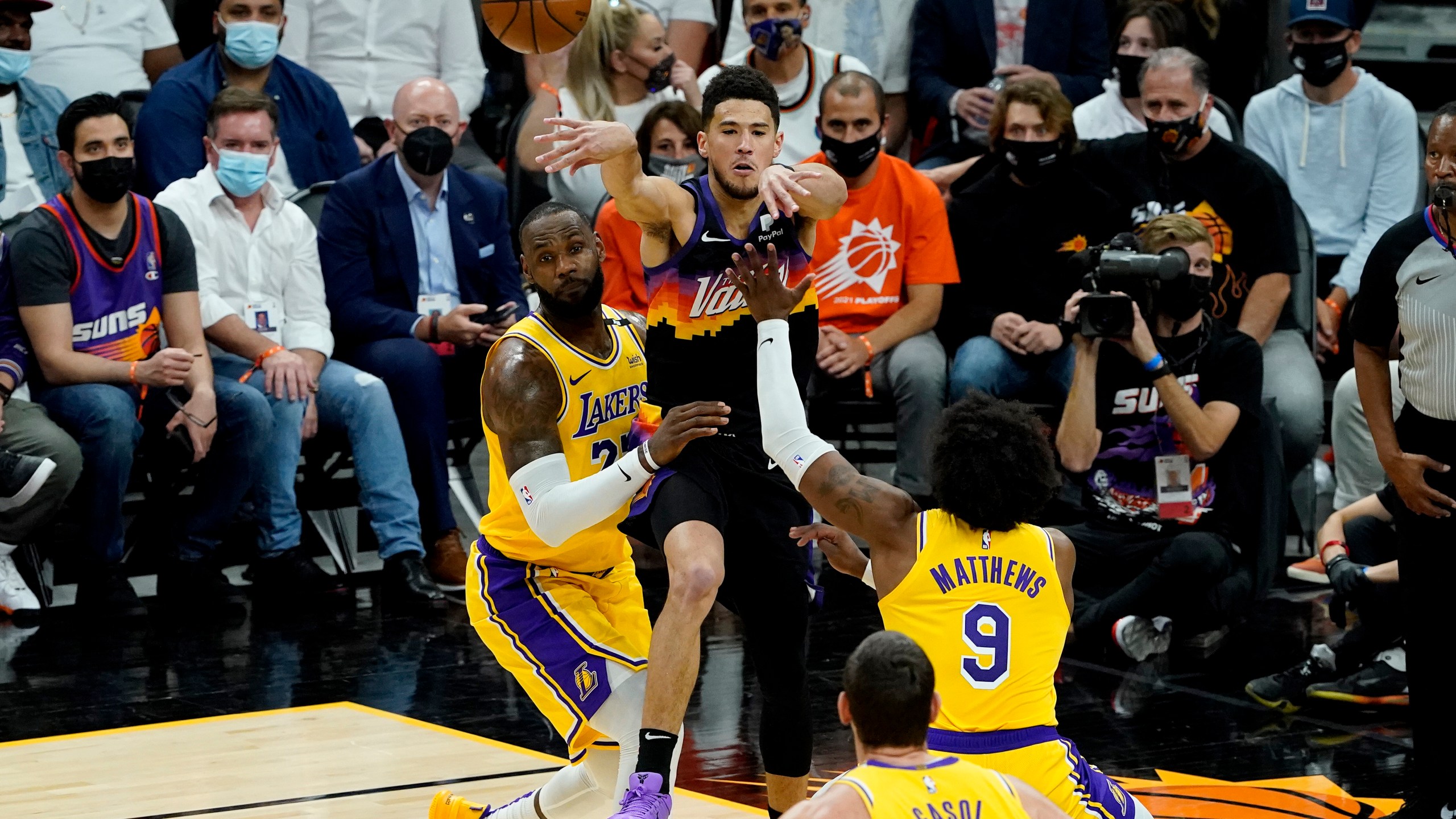 Phoenix Suns guard Devin Booker passes over Los Angeles Lakers forward LeBron James, left, and guard Wesley Matthews (9) during the first half of Game 5 of an NBA basketball first-round playoff series on June 1, 2021, in Phoenix. (AP Photo/Matt York)