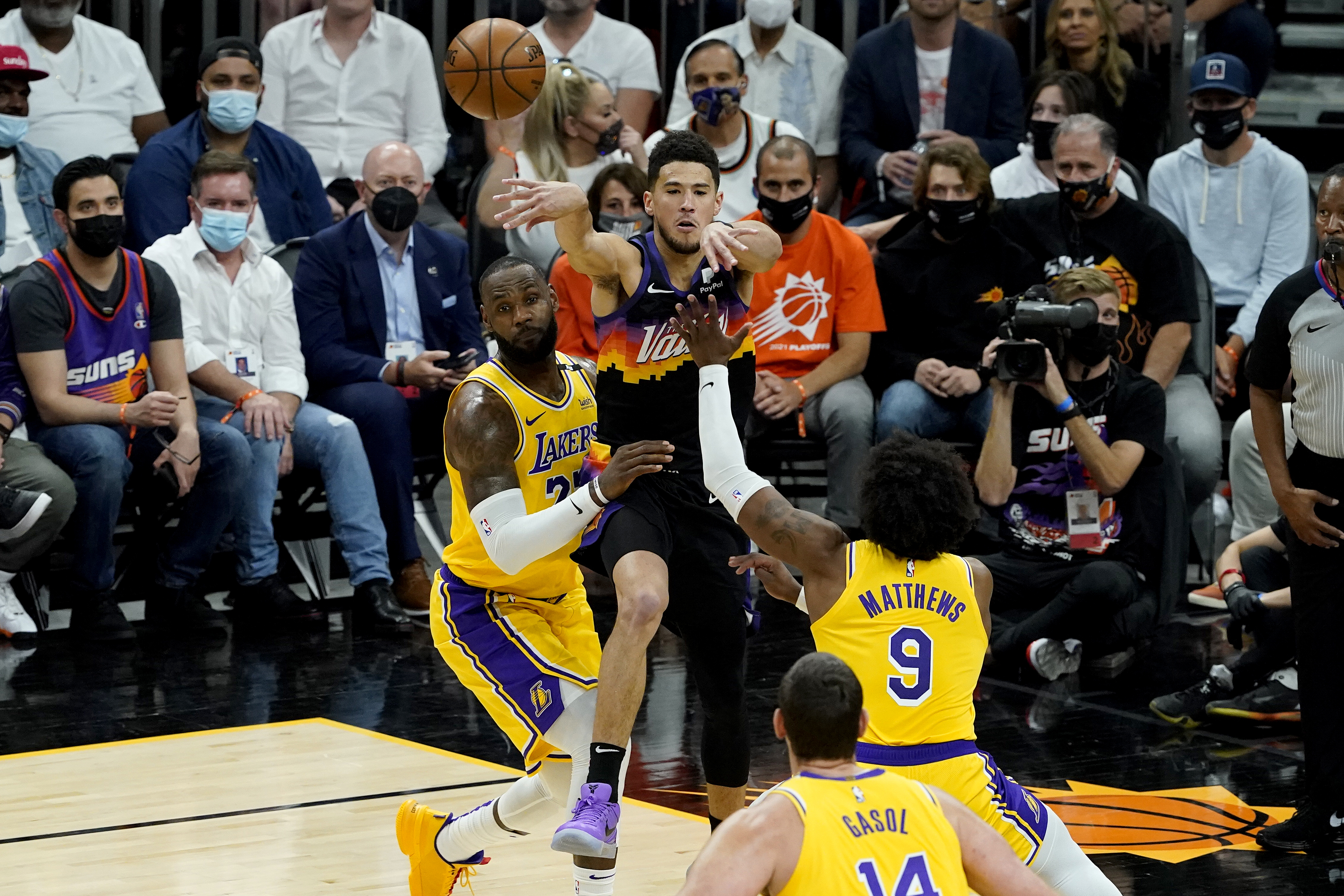 Phoenix Suns guard Devin Booker passes over Los Angeles Lakers forward LeBron James, left, and guard Wesley Matthews (9) during the first half of Game 5 of an NBA basketball first-round playoff series on June 1, 2021, in Phoenix. (AP Photo/Matt York)