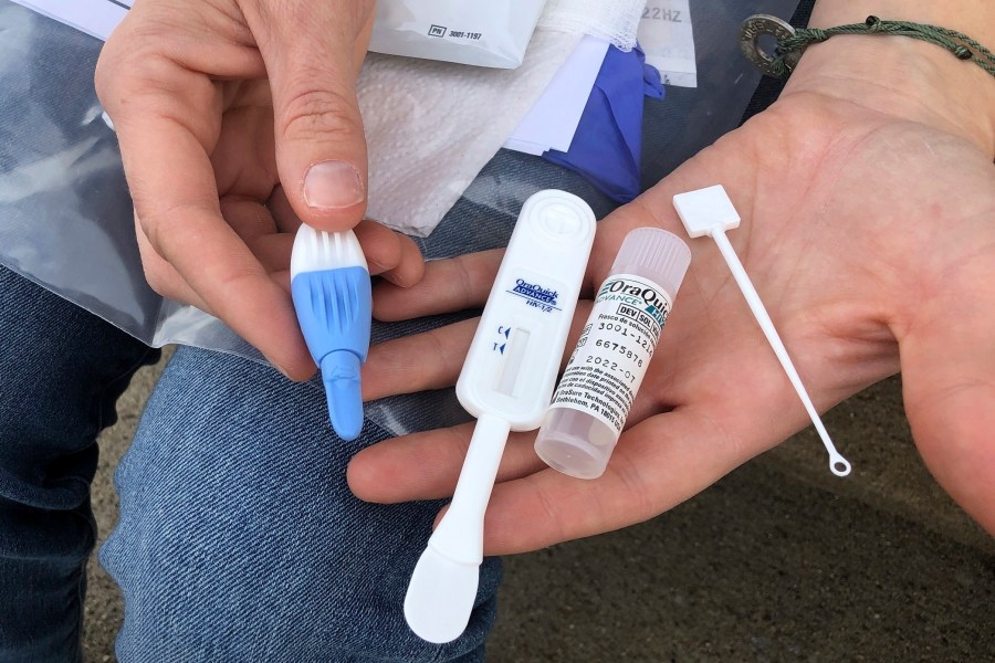 In this March 9, 2021 file photo, Solutions Oriented Addiction Response organizer Brooke Parker holds an HIV testing kit in Charleston, West Virginia. (John Raby/Associated Press)