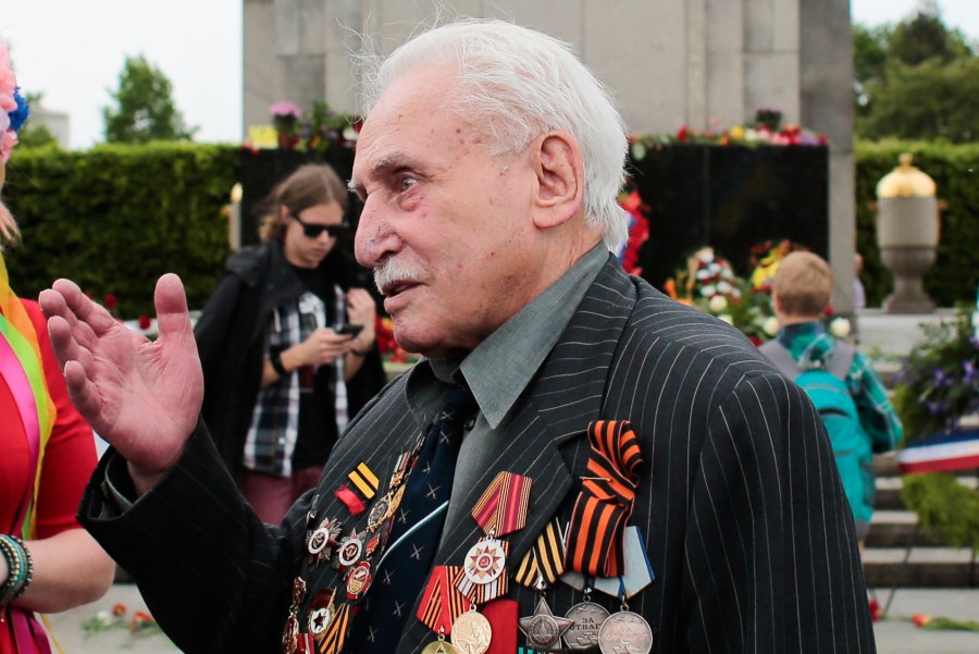 In this Friday, May 8, 2015 file photo, Soviet war veteran David Dushman, 92, center, speaks to people holding Ukrainian flags as he attends a wreath laying ceremony at the Russian War Memorial in the Tiergarten district of Berlin, Germany. Dushman, the last surviving Allied soldier involved in the liberation of Auschwitz, has died. The Jewish Community of Munich and Upper Bavaria said Sunday, June 6, 2021 that Dushman had died a day earlier in a Munich hospital at the age of 98. As young Red Army soldier, Dushman flattened the forbidding fence around the notorious Nazi death camp with his tank on Jan. 27, 1945. (AP Photo/Markus Schreiber, File)