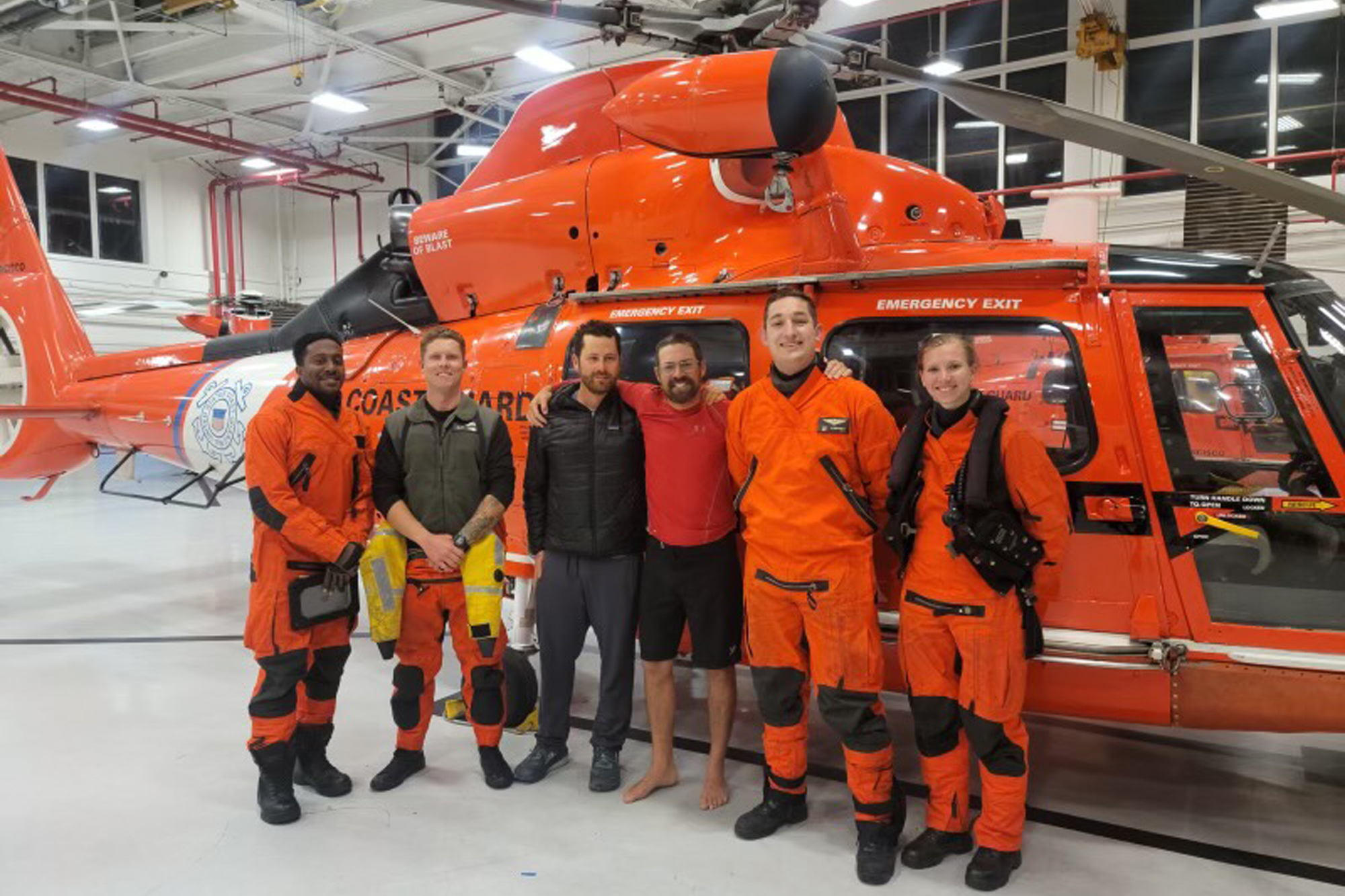 In this photo provided by the U.S. Coast Guard, kayaker Cyril Derreumaux, in shorts, poses with the Coast Guard helicopter crew that rescued him off the California coast in San Francisco on June 5, 2021.