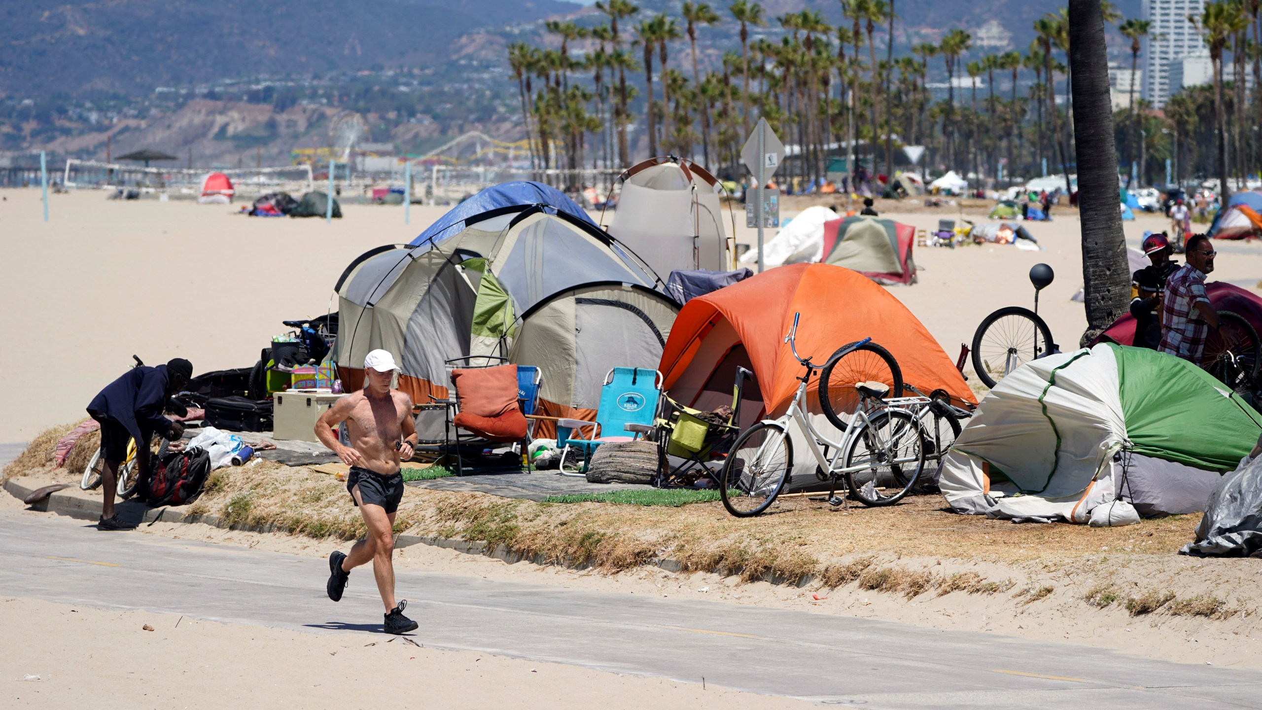 A jogger walks past a homeless encampment Tuesday, June 8, 2021, in the Venice Beach section of Los Angeles. (AP Photo/Marcio Jose Sanchez)