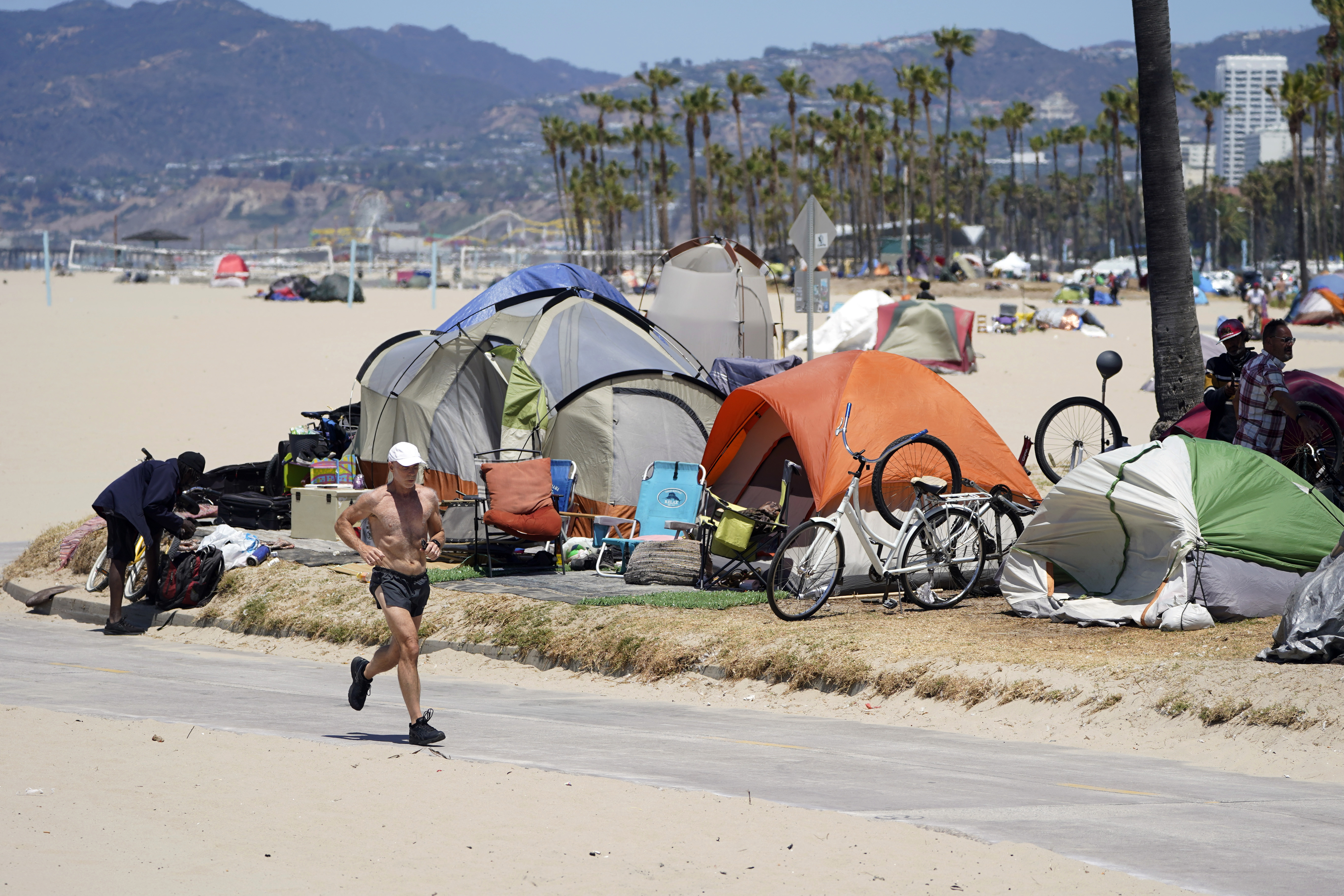 A jogger walks past a homeless encampment Tuesday, June 8, 2021, in the Venice Beach section of Los Angeles. (AP Photo/Marcio Jose Sanchez)