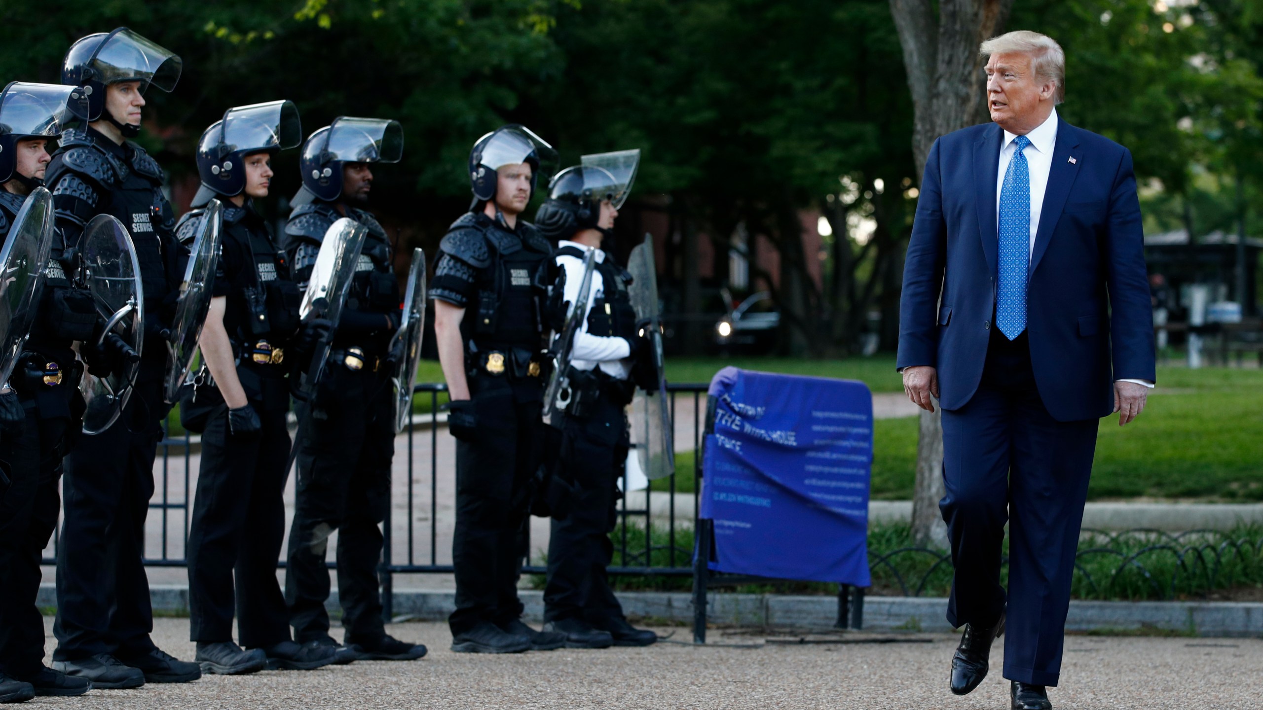 In this June 1, 2020 file photo, President Donald Trump walks past police in Lafayette Park after visiting outside St. John's Church across from the White House in Washington. (AP Photo/Patrick Semansky)