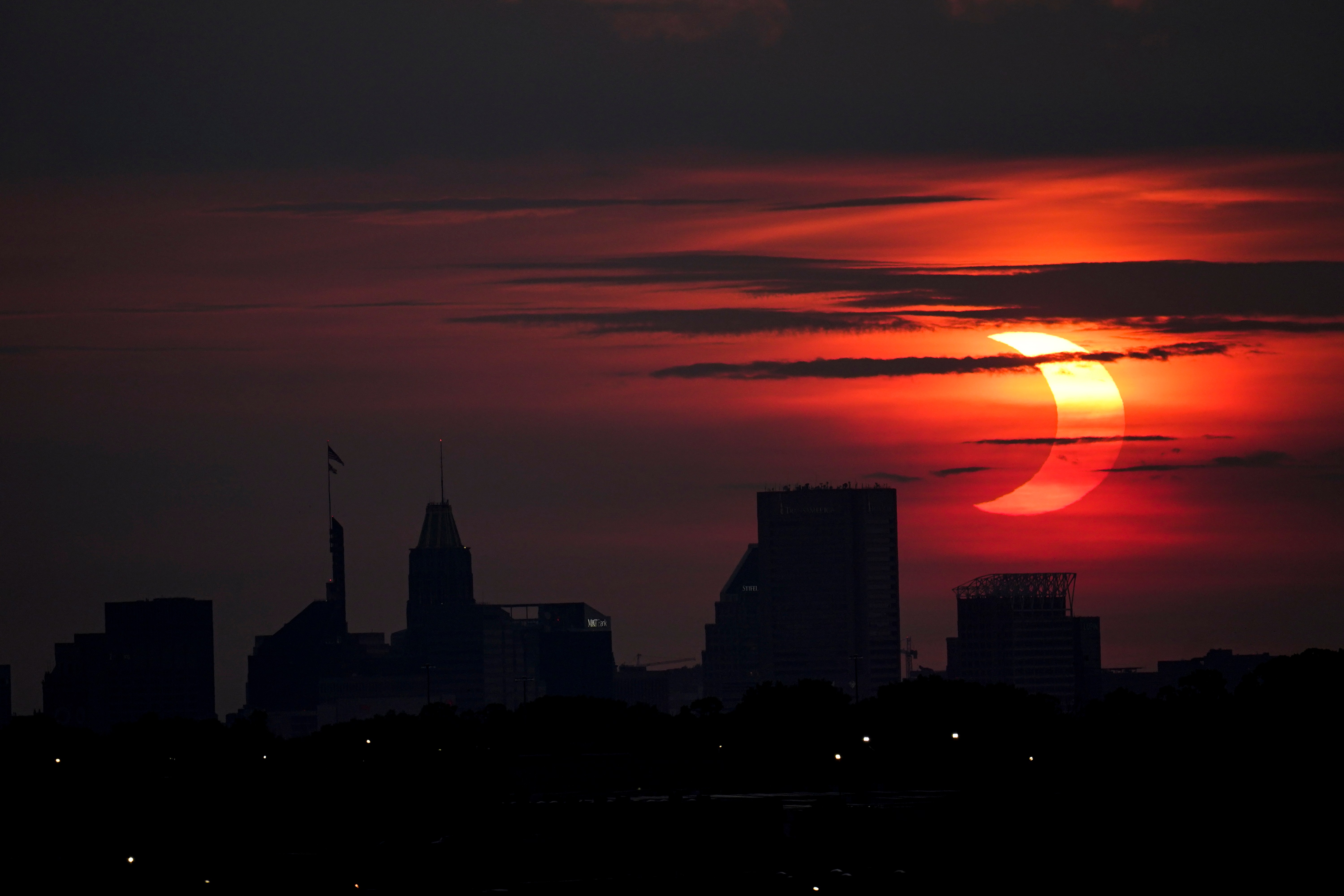 A partial solar eclipse rises over the Baltimore skyline, Thursday, June 10, 2021, seen from Arbutus, Md. (AP Photo/Julio Cortez)