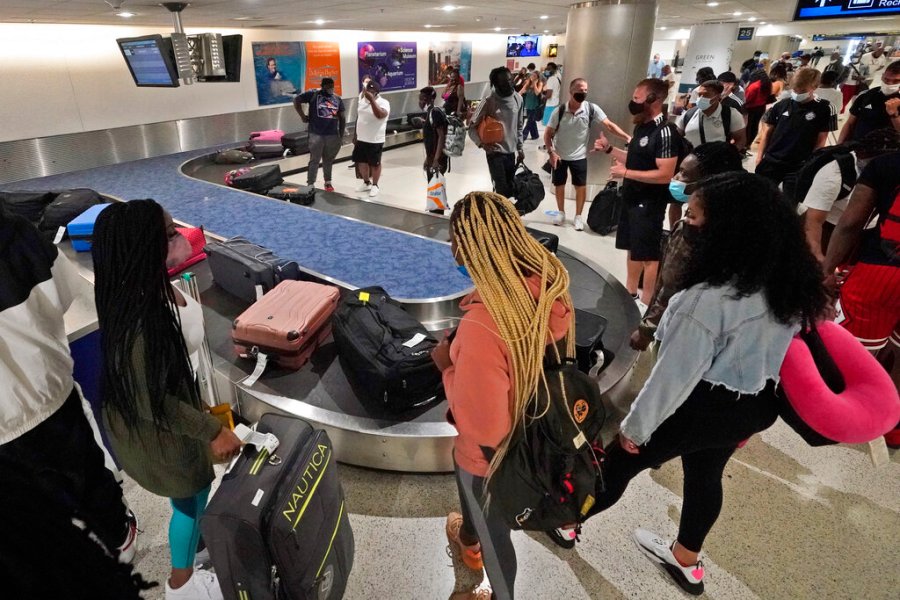 In this May 28, 2021 file photo, travelers wait for their luggage at a baggage carousel at Miami International Airport in Miami. (AP Photo/Wilfredo Lee, File)