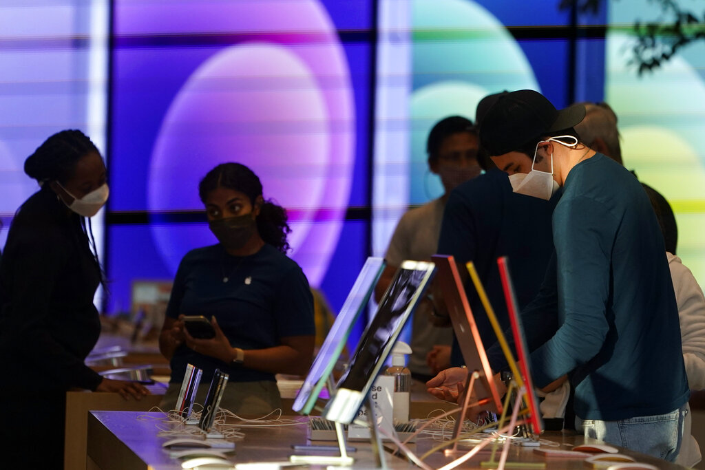 In this June 9, 2021, file photo, workers and customers wear masks inside an Apple Store amid the COVID-19 pandemic on The Promenade, in Santa Monica, Calif. (AP Photo/Marcio Jose Sanchez, File)