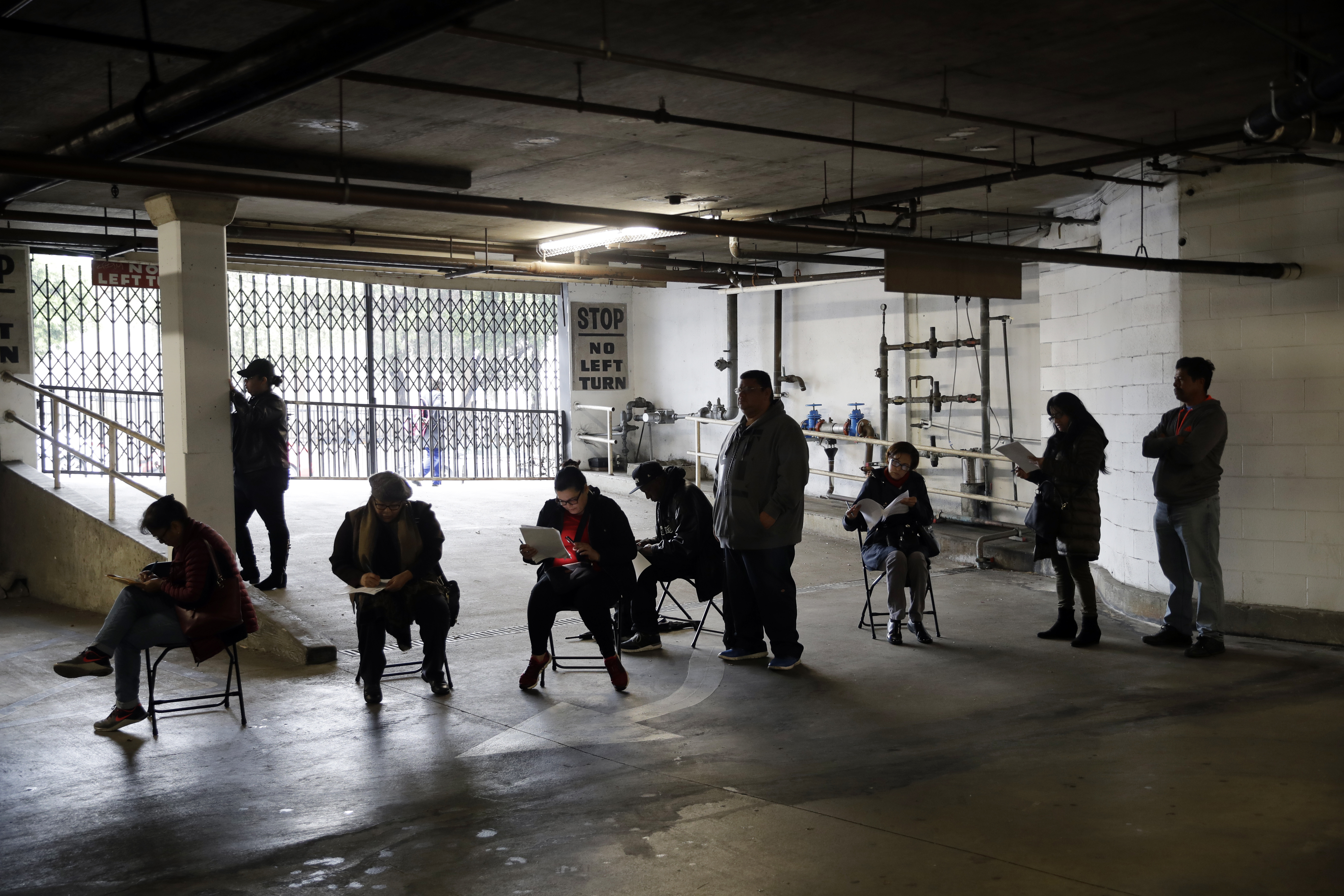 Unionized hospitality workers wait in line in a basement garage to apply for unemployment benefits at the Hospitality Training Academy in Los Angeles on March 13, 2020. (Marcio Jose Sanchez / Associated Press)