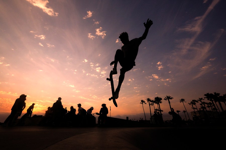 In this Wednesday, June 16, 2021, file photo, a skateboarder is silhouetted as he jumps high at the skateboard park during sunset in the Venice Beach section of Los Angeles. The Southwest U.S. continued to bake Saturday, June 19, and weather forecasters kept warnings in effect for excessive heat in Arizona, Nevada and desert areas, at least through the weekend. (AP Photo/Ringo H.W. Chiu, File)