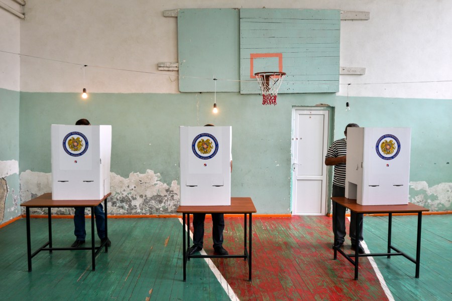 Voters read their ballots at a polling station in a school's sport hall during a parliamentary elections in Yerevan, Armenia, Sunday, June 20, 2021. (Karo Sahakyan/PAN Photo via AP)