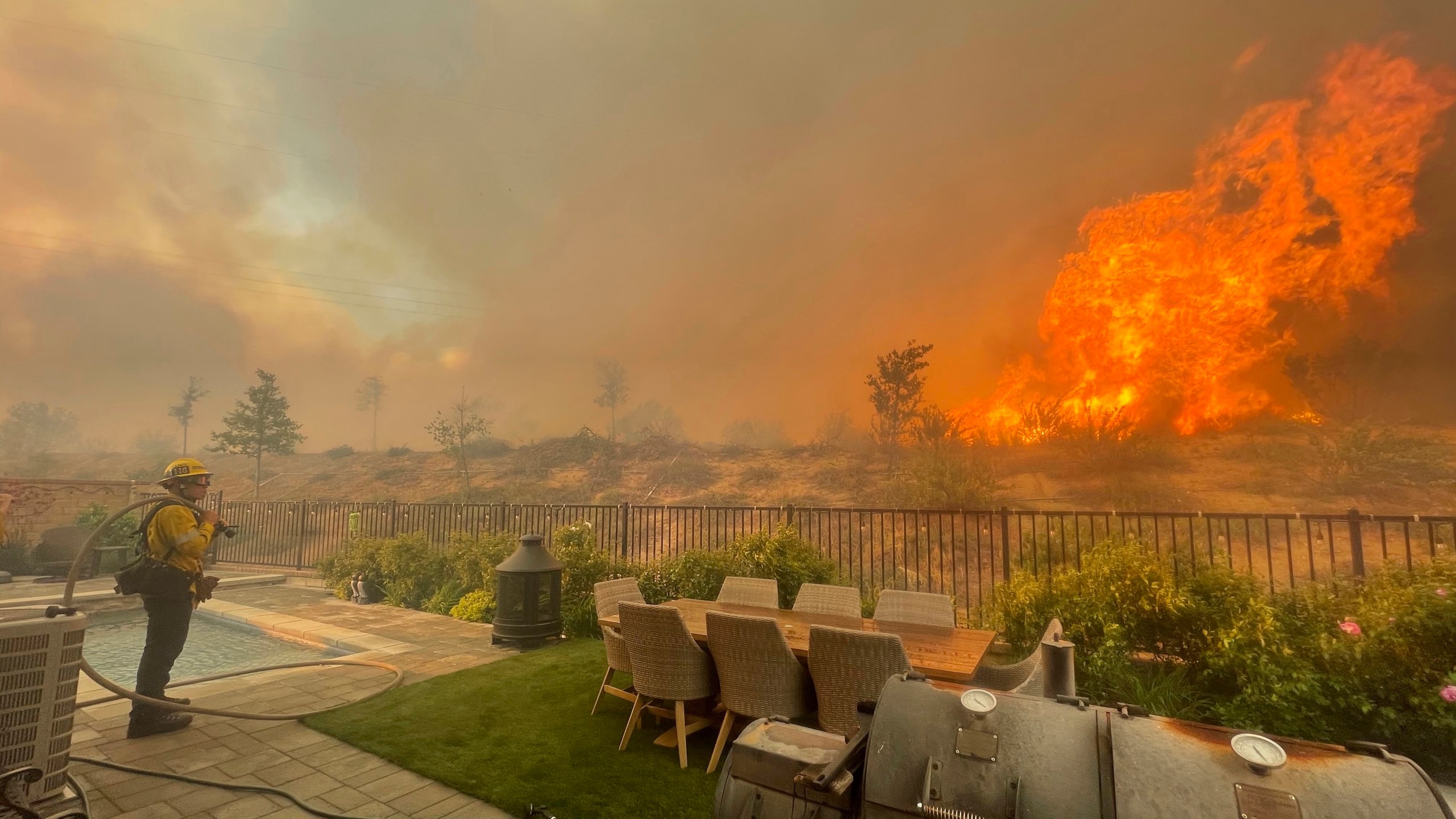 In this April 28, 2021, file photo, a firefighter prepares to battle the North Fire from a backyard on Via Patina, in Santa Clarita. (Emily Alvarenga//The Santa Clarita Valley Signal via AP, File)