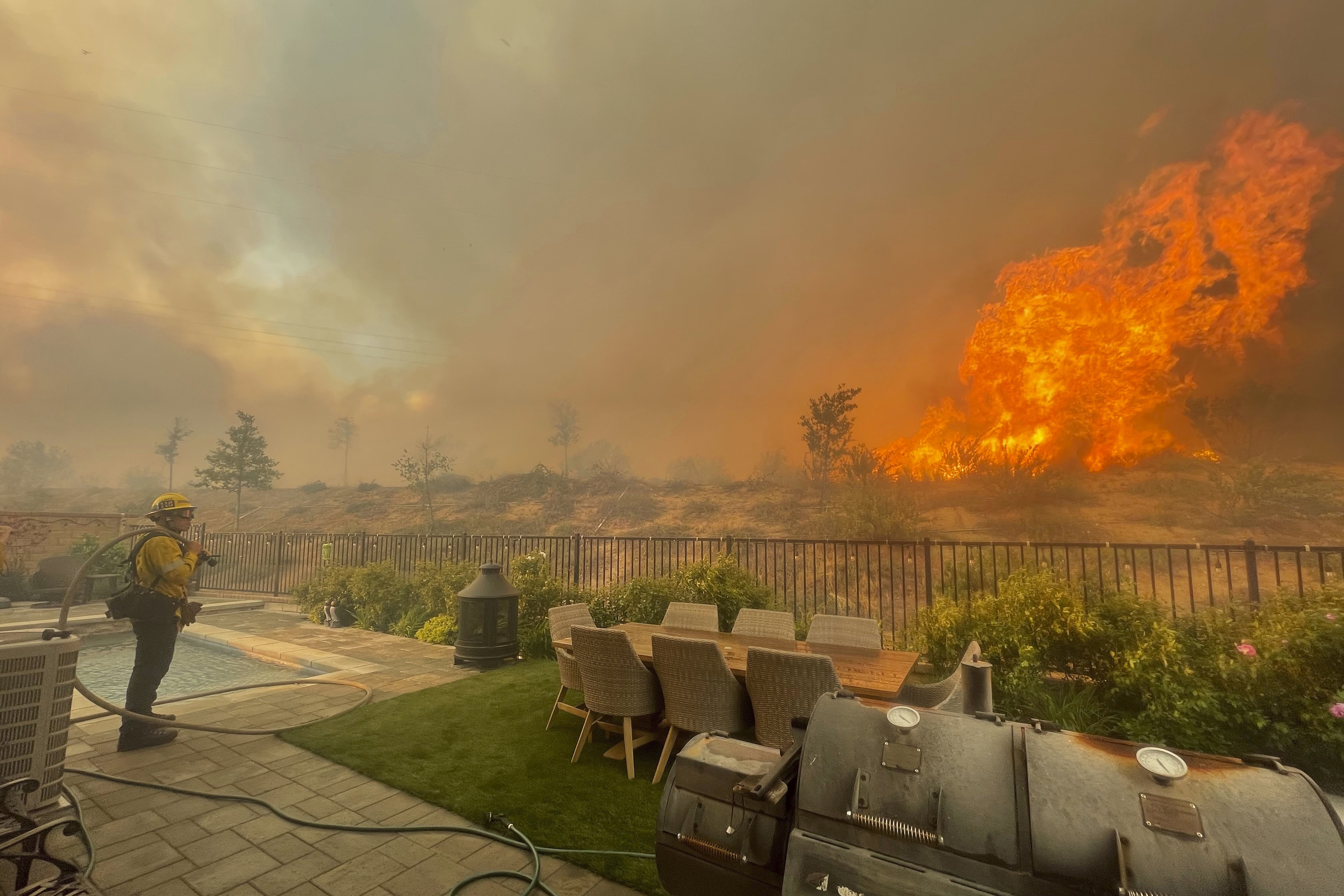 In this April 28, 2021, file photo, a firefighter prepares to battle the North Fire from a backyard on Via Patina, in Santa Clarita. (Emily Alvarenga//The Santa Clarita Valley Signal via AP, File)