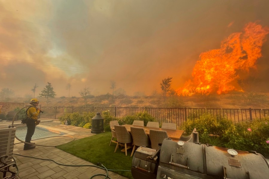 In this April 28, 2021, file photo, a firefighter prepares to battle the North Fire from a backyard on Via Patina, in Santa Clarita. (Emily Alvarenga//The Santa Clarita Valley Signal via AP, File)