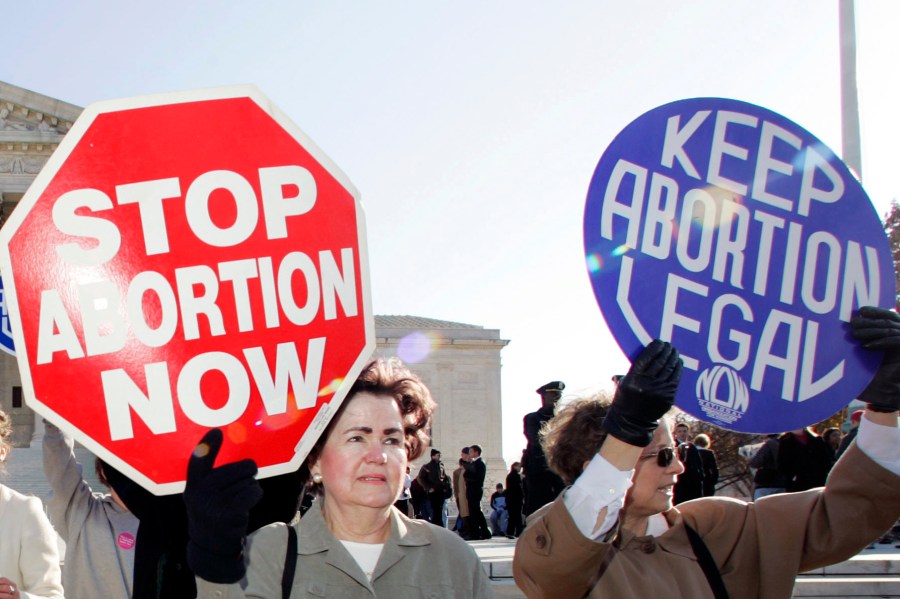 In this Nov. 30, 2005 file photo, an anti-abortion supporter stands next to a pro-choice demonstrator outside the U.S. Supreme Court in Washington. The new poll from The Associated Press-NORC Center for Public Affairs Research finds 61% of Americans say abortion should be legal in most or all circumstances in the first trimester of a pregnancy. However, 65% said abortion should usually be illegal in the second trimester, and 80% said that about the third trimester. (AP Photo/Manuel Balce Ceneta)