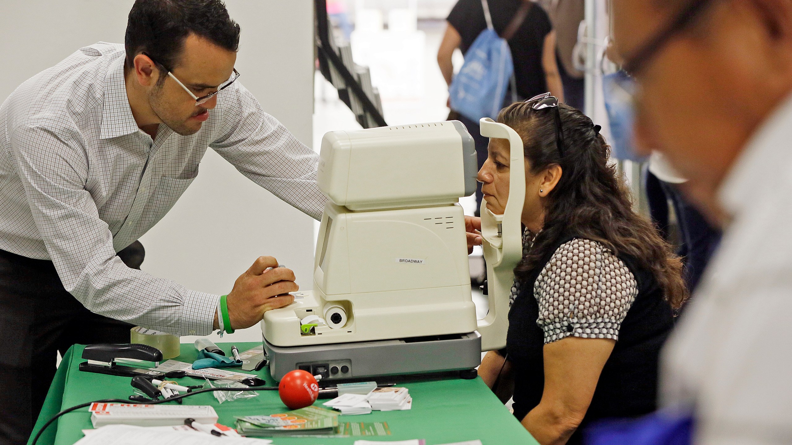 In this Oct. 1, 2013, file photo, Rosa Guerra, 52, right, gets a free eye exam during the Binational Health Week event held at the Mexican Consulate in Los Angeles. (AP Photo/Damian Dovarganes, File)