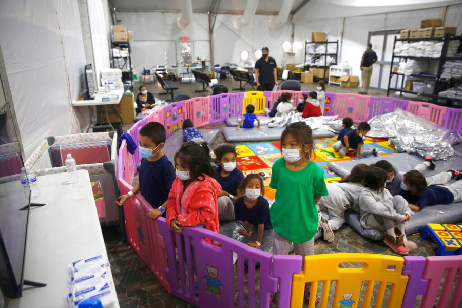 In this March 30, 2021 file photo Young unaccompanied migrants, from ages 3 to 9, watch television inside a playpen at the U.S. Customs and Border Protection facility, the main detention center for unaccompanied children in the Rio Grande Valley, in Donna, Texas. (AP Photo/Dario Lopez-Mills, Pool, File)