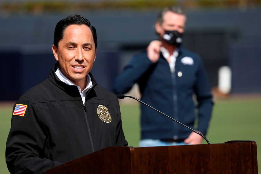 California Governor Gavin Newsom (back) listens as San Diego Mayor Todd Gloria speaks to members of the media during a press conference at Petco Park, February 8, 2021 in San Diego, California, during a visit to the Petco Park Vaccination Supersite. (Sandy Huffaker/POOL/AFP via Getty Images)