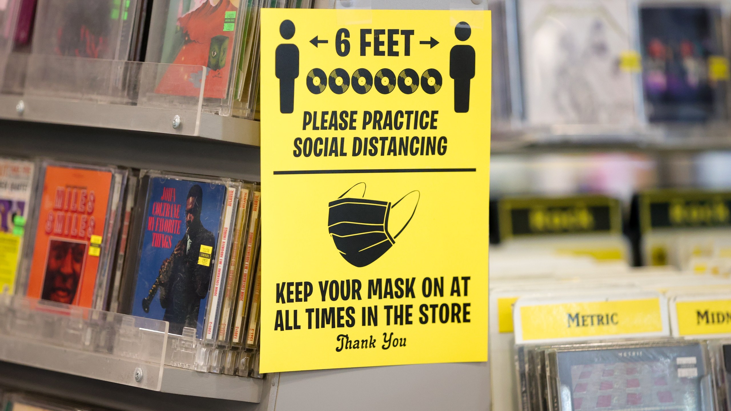 A sign encouraging social distancing and mask-wearing is seen at Amoeba Music during its grand re-opening at the new location on Hollywood Boulevard on April 1, 2021. (Rich Fury / Getty Images)