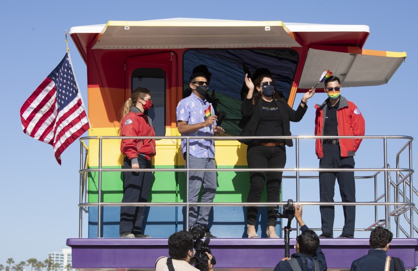 Long Beach Mayor Robert Garcia and Councilwoman Cindy Allen, flanked by lifeguards Devon Bebee, left, and Jeremy Rocha, on June 10, 2021, to celebrate the unveiling of a new rainbow-colored lifeguard tower at Long Beach to replace the one that burned down in March. (Myung J. Chun / Los Angeles Times)