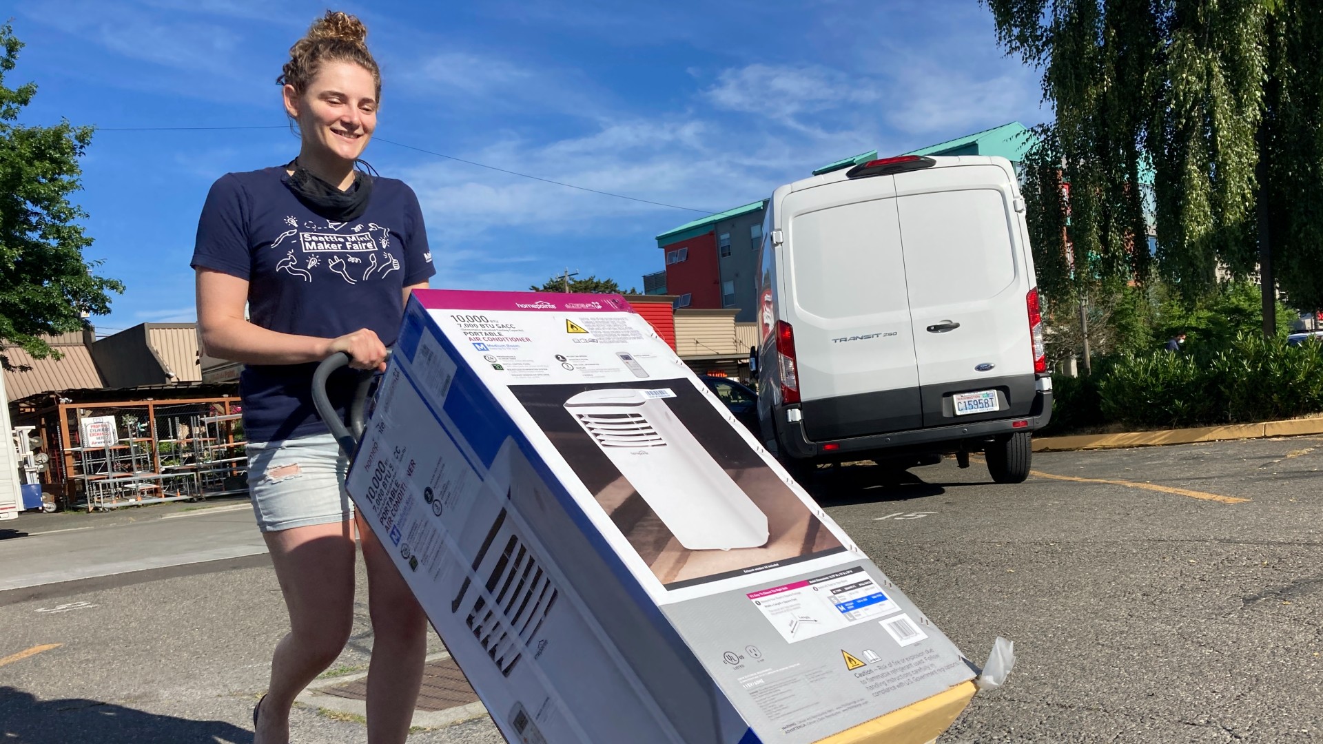 Sarah O'Sell transports her new air conditioning unit to her nearby apartment on a dolly in Seattle on Friday, June 25, 2021. (AP Photo/Manuel Valdes)