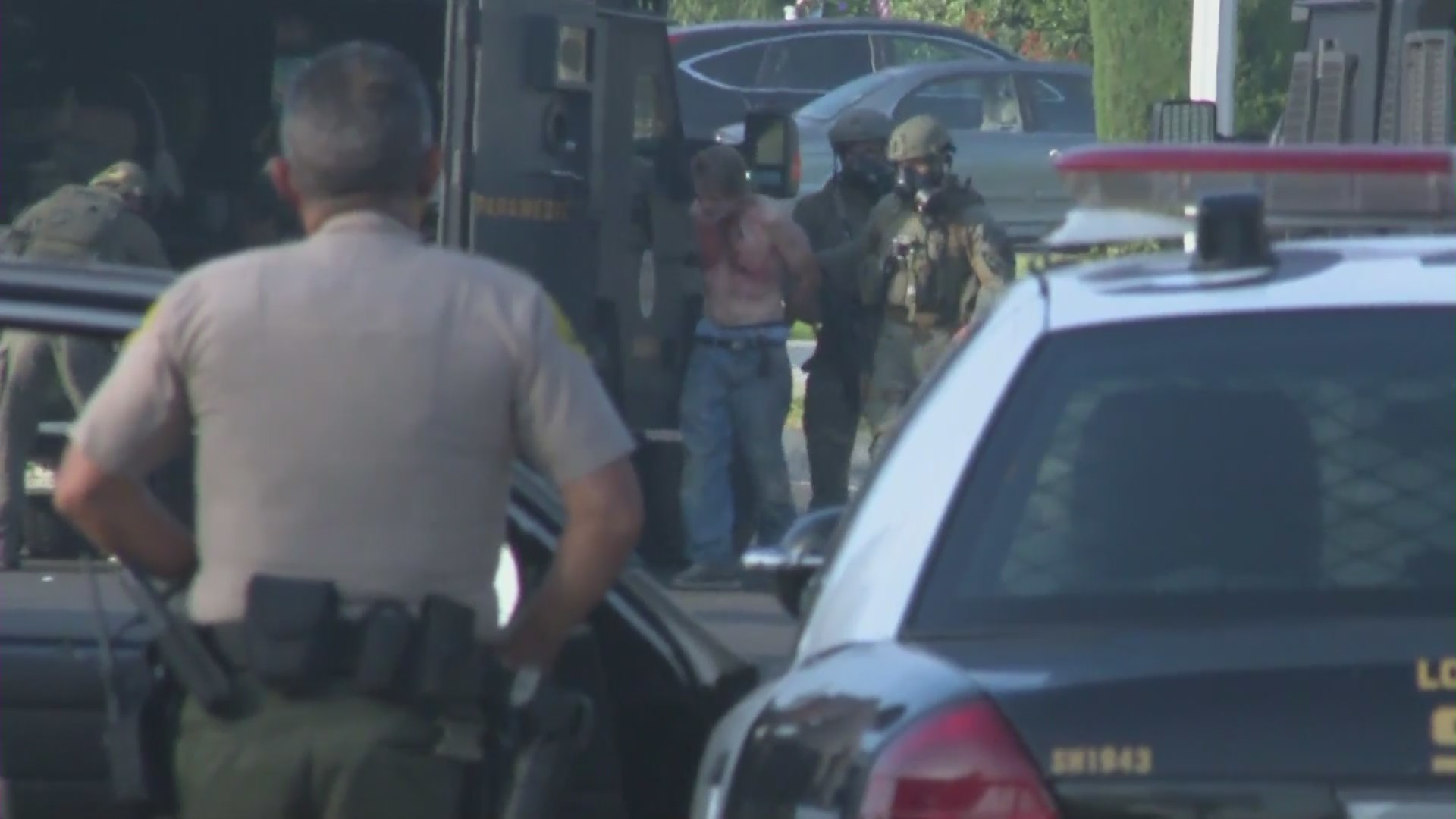 A man is detained by authorities following an hourslong barricade in Covina. (KTLA)