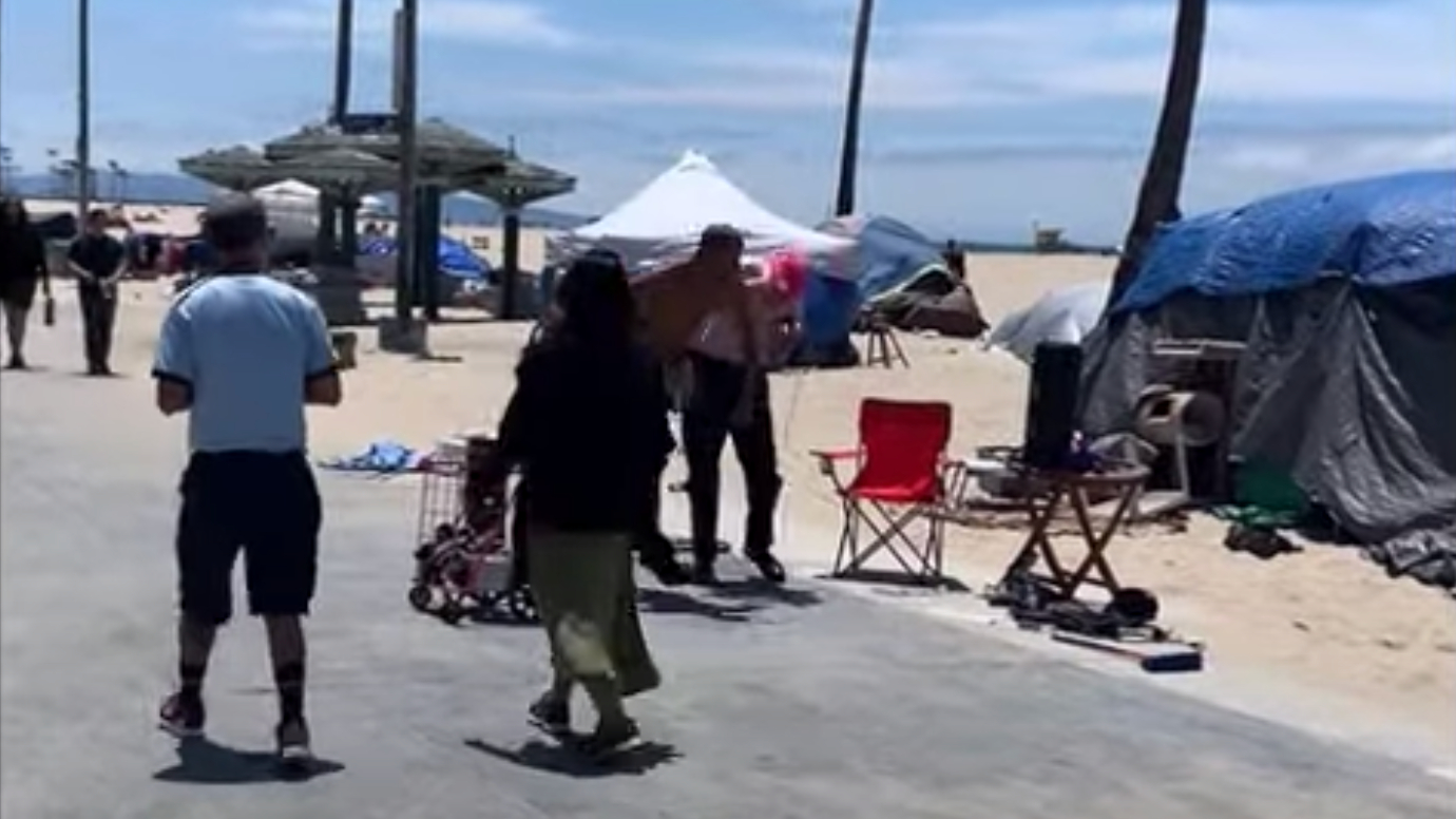 A man sucker-punches a street performer on the Venice Beach Boardwalk on June 6, 2021, in a still from video released by the Los Angeles Police Department.