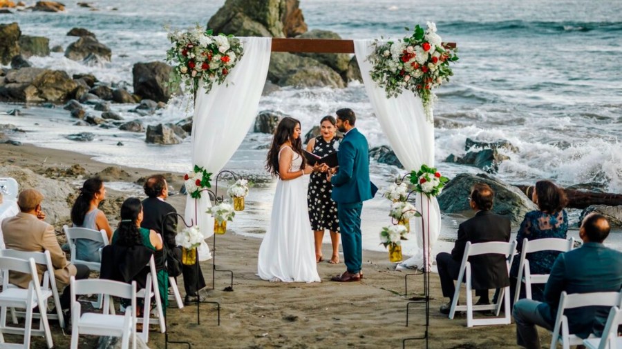 This photo shows bride Namisha Balagopal and groom Suhaas Prasad getting married in a small legal ceremony Aug. 15, 2020, on Muir Beach near San Francisco. (Vellora Productions via AP)