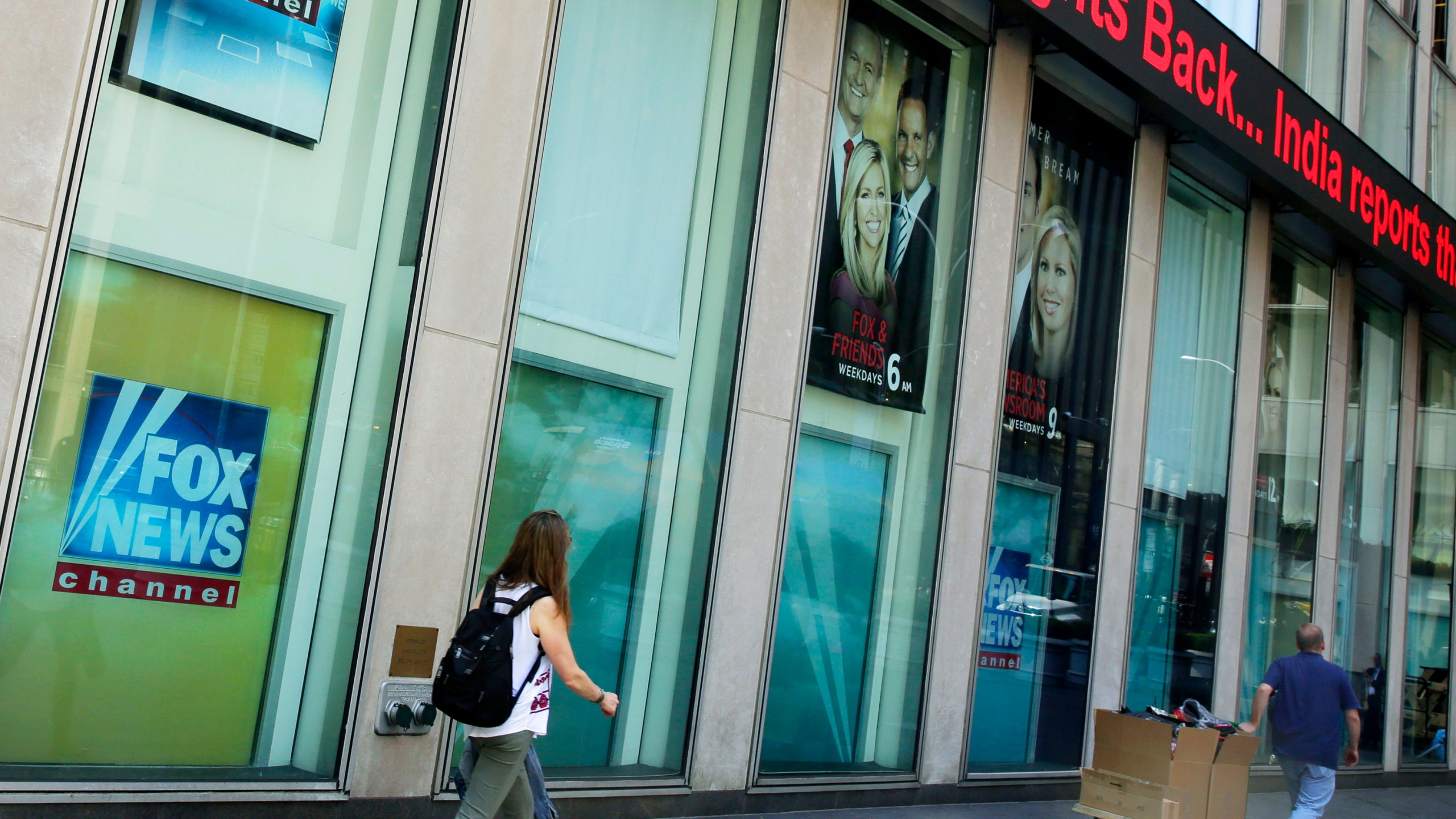 People pass the News Corporation headquarters building and Fox News studios in New York on Aug. 1, 2017. (AP Photo/Richard Drew, File)