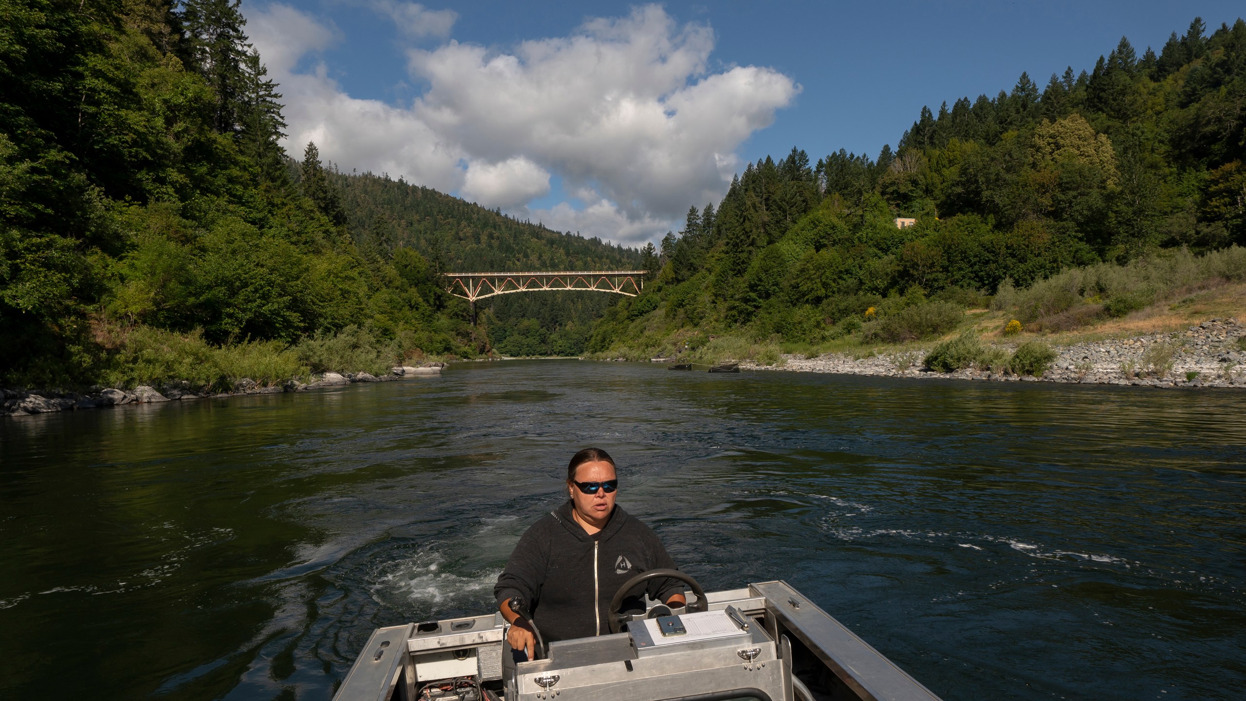 Jamie Holt, lead fisheries technician for the Yurok Tribe, maneuvers a boat near a fish trap in the lower Klamath River on Tuesday, June 8, 2021, in Weitchpec, Calif. A historic drought and low water levels are threatening the existence of fish species along the 257-mile long river. "When I first started this job 23 years ago, extinction was never a part of the conversation," she said of the salmon. "If we have another year like we're seeing now, extinction is what we're talking about." (AP Photo/Nathan Howard)