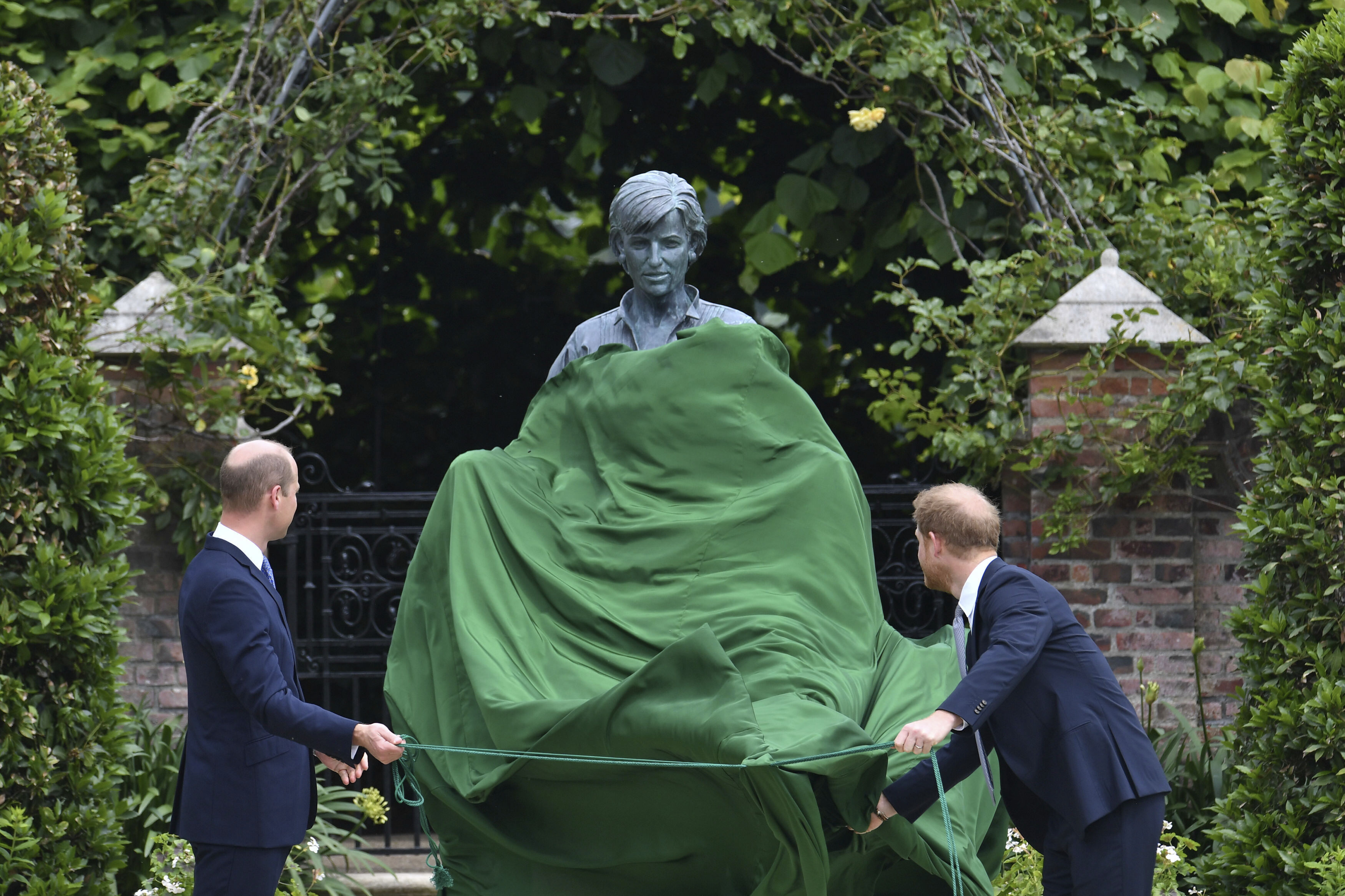 Britain's Prince William, left and Prince Harry unveil a statue they commissioned of their mother Princess Diana, on what woud have been her 60th birthday, in the Sunken Garden at Kensington Palace, London, Thursday July 1, 2021. (Dominic Lipinski /Pool Photo via AP)