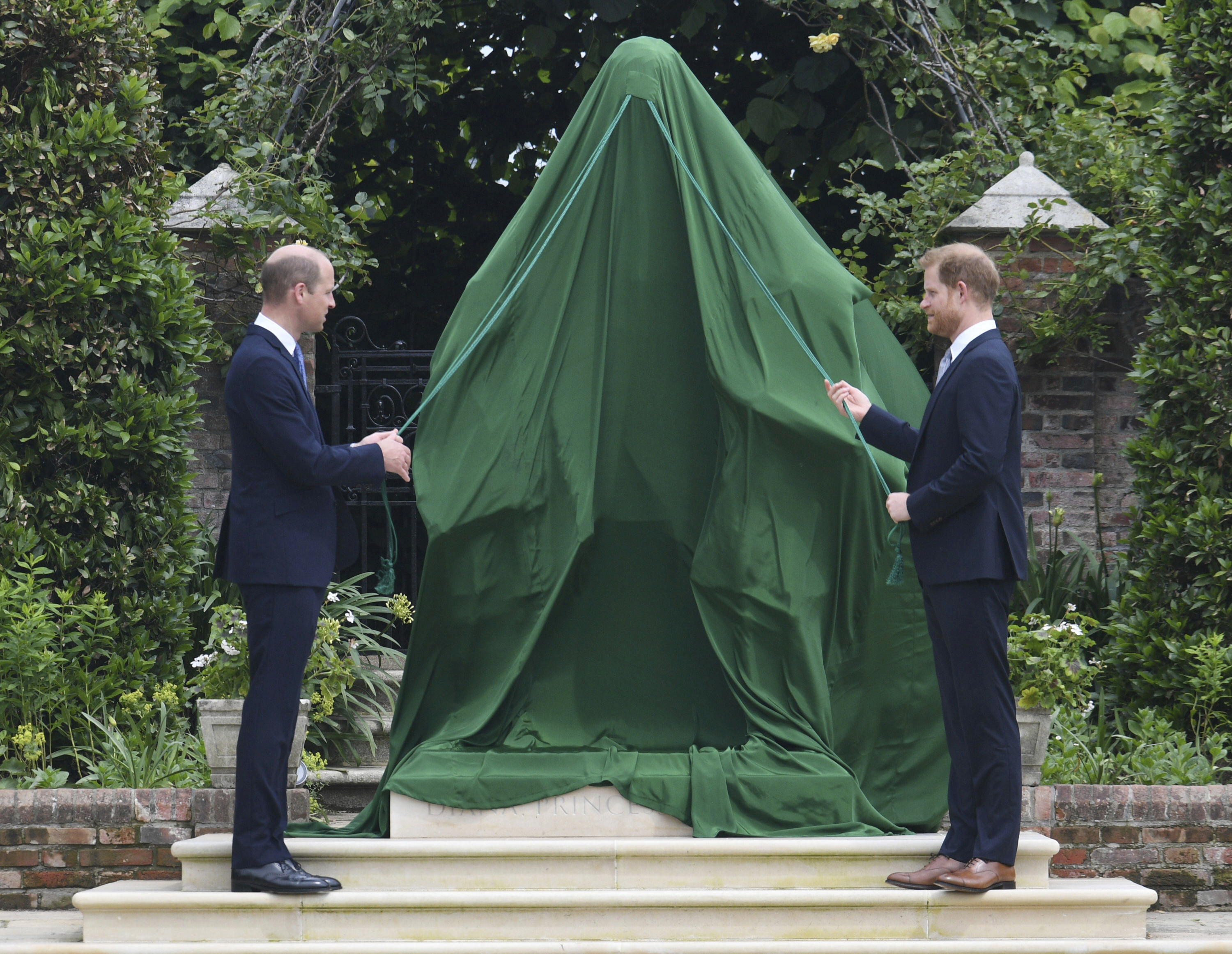 Britain's Prince William, left and Prince Harry unveil a statue they commissioned of their mother Princess Diana, on what woud have been her 60th birthday, in the Sunken Garden at Kensington Palace, London, Thursday July 1, 2021. (Dominic Lipinski /Pool Photo via AP)