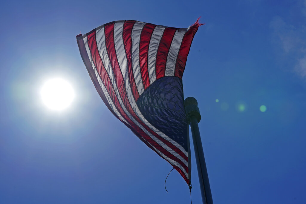 In this Wednesday, June 30, 2021 photo, a U.S. flag flies with the sun in the background in downtown Seattle. (AP Photo/Ted S. Warren, File)