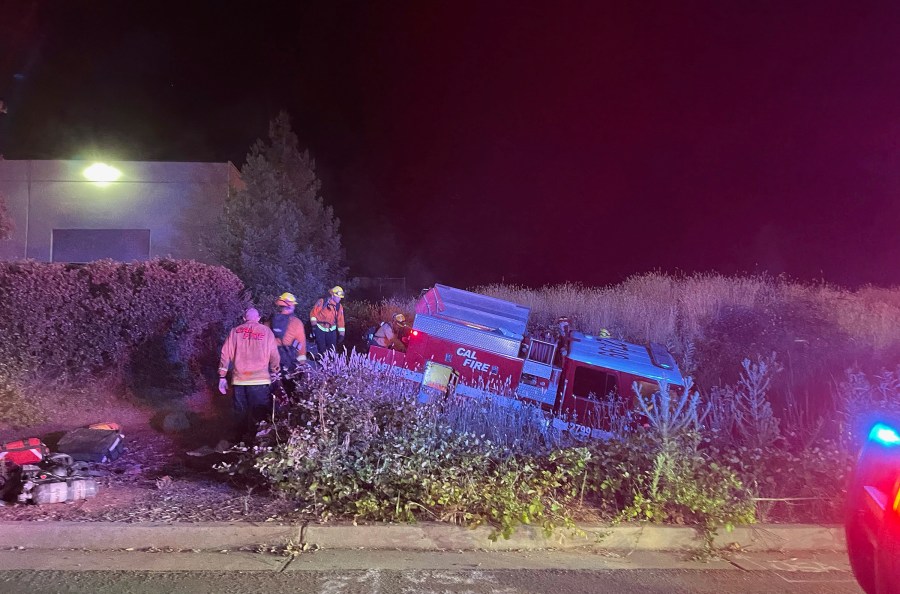 In this photo provided by Bill Wilde, firefighters look over a California Department of Forestry and Fire Protection truck that crashed into a ditch after it was stolen by a California inmate on July 4, 2021, in Shingle Springs, Calif. (Bill Wilde Photo via AP)