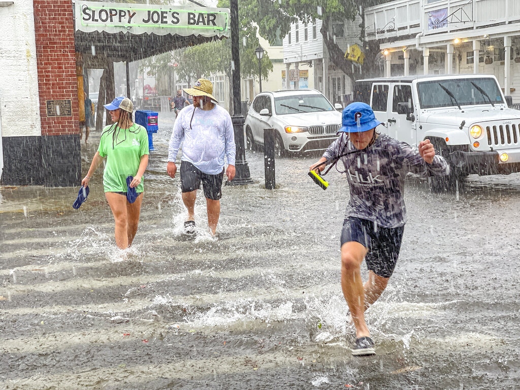 Pedestrians dash across the intersection of Greene and Duval streets as heavy winds and rain associated with Tropical Storm Elsa passes Key West, Fla., on Tuesday, July 6, 2021. (Rob O'Neal/The Key West Citizen via AP)