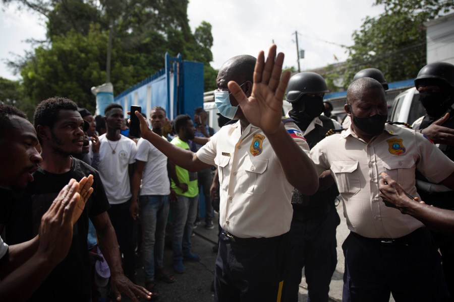 People pressure police to hand over two men who were arrested and the bodies of two men who were brought in by police after they were killed by police, in order to burn them in retaliation for the assassination of Haitian President Jovenel Moïse, at a police station of Petion Ville in Port-au-Prince, Haiti, Thursday, July 8, 2021. According to National Police Director Leon Charles, the dead and detained are suspects in Moïse's July 7 assassination. (AP Photo/Joseph Odelyn)