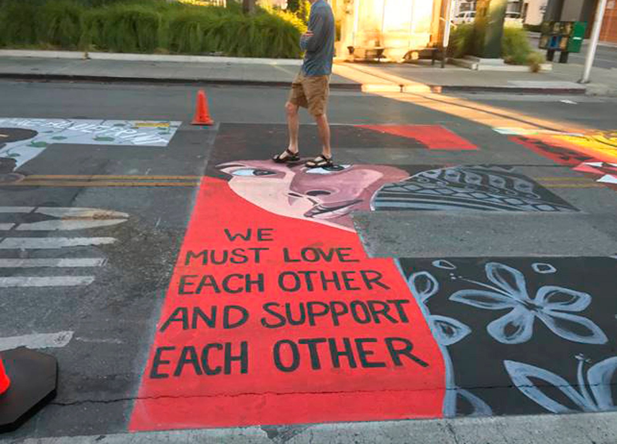 In this photo provided by the Palo Alto Daily Post, a man walks by a Black Lives Matter mural showing Assata Shakur, who was convicted of killing a New Jersey law enforcement officer in 1973, on July 8, 2020, in Palo Alto, Calif. Five police officers have filed a lawsuit against the city of Palo Alto for allowing the creation of the mural they say contained anti-police images. (Dave Price/Palo Alto Daily Post via AP)