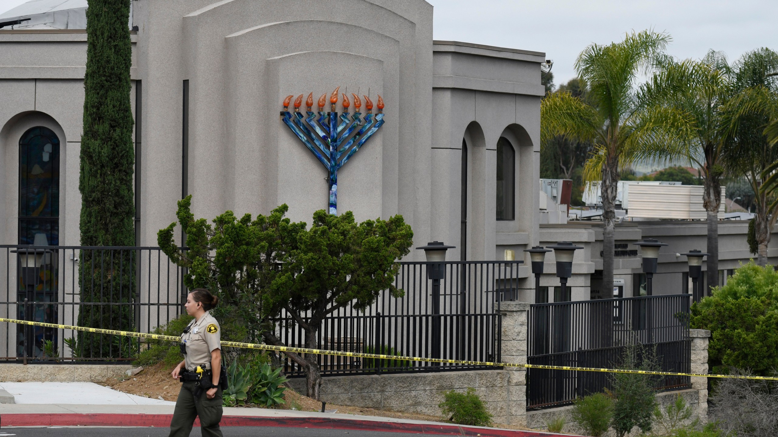 In this Sunday, April 28, 2019 file photo, a San Diego county sheriff's deputy stands in front of the Chabad of Poway synagogue, in Poway, Calif. A California judge on Wednesday, July 7, 2021 decided victims of the 2019 synagogue shooting near San Diego that killed one worshiper and wounded three can sue the manufacturer of the semiautomatic rifle and the gun shop that sold it to the teenage gunman, according to a newspaper report.(AP Photo/Denis Poroy, File)