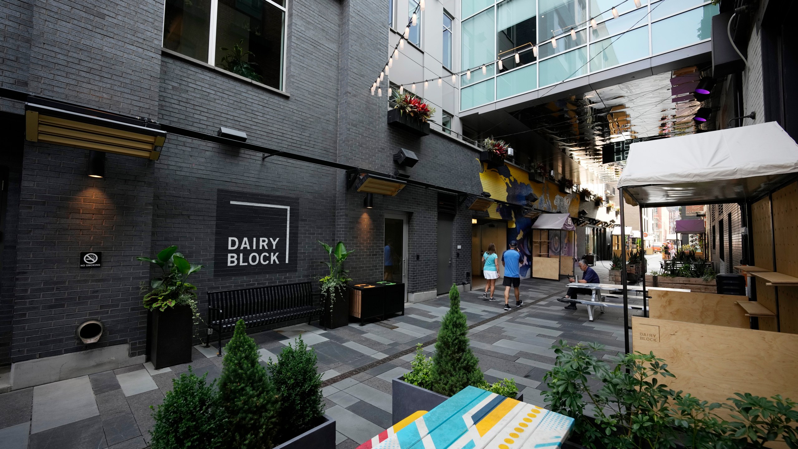 Pedestrians move through the alleyway in the Dairy Block and past the outside of the Maven Hotel Sunday, July 11, 2021, in lower downtown Denver. (AP Photo/David Zalubowski)