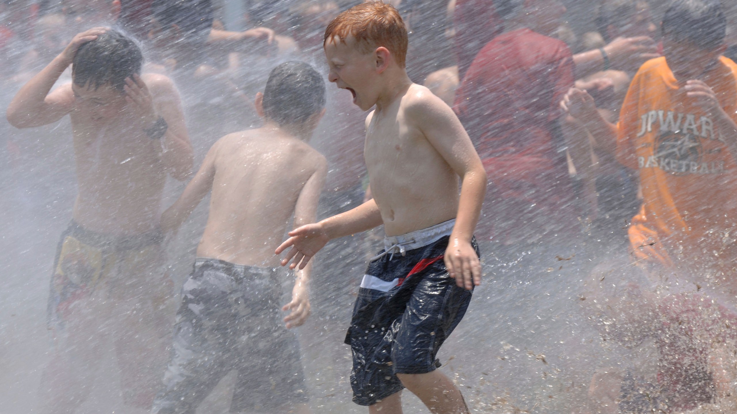 In this June 9, 2006, file photo, kids from a day camp get soaked by the the fire department at Tyler Junior College in Tyler, Texas. The U.S. has seen a string of COVID-19 outbreaks tied to summer camps in recent weeks in Texas, Illinois, Florida, Missouri and Kansas, offering what some fear could be a preview of the upcoming school year. (Brad Smith/Tyler Morning Telegraph via AP, File)