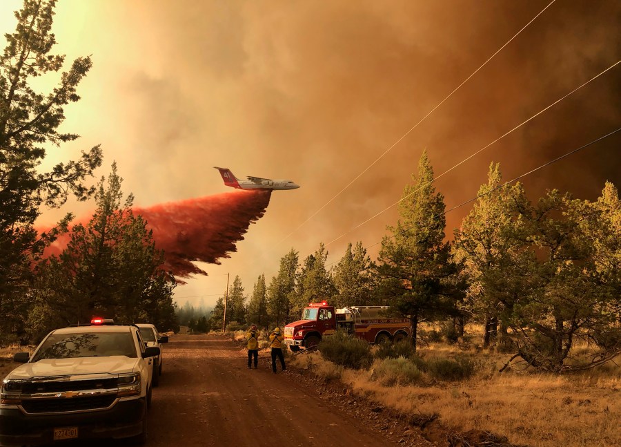 This photo provided by the Oregon Department of Forestry shows a firefighting tanker making a retardant drop over the Grandview Fire near Sisters, Ore., Sunday, July 11, 2021. The wildfire doubled in size to 6.2 square miles (16 square kilometers) Monday, forcing evacuations in the area, while the state's biggest fire continued to burn out of control, with containment not expected until November. (Oregon Department of Forestry via AP)