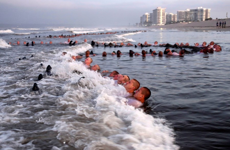 In this May 4, 2020 photo provided by the U.S. Navy, SEAL candidates participating in "surf immersion" during Basic Underwater Demolition/SEAL (BUD/S) training at the Naval Special Warfare (NSW) Center in Coronado, Calif. For the first time, a female sailor has successfully completed the grueling 37—week training course to become a Naval Special Warfare combatant-craft crewman — the boat operators that transport Navy SEALs and conduct their own missions at sea. Navy officials said they would not identify the woman, who completed the final phases of training and graduated Thursday. She was one of 17 sailors to receive their pins during the ceremony. (MC1 Anthony Walker/U.S. Navy via AP)