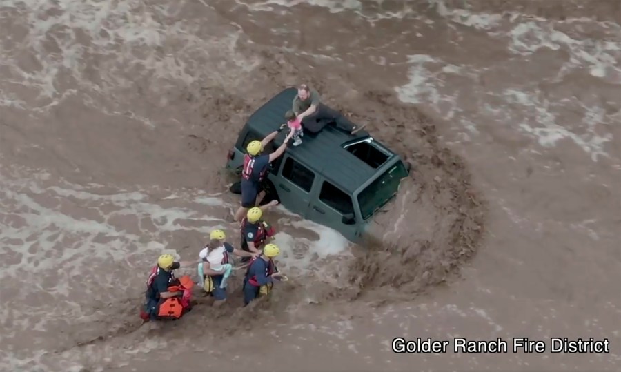 This drone image provided by the Golder Ranch Fire District shows firefighters safely rescue a man and his two daughters from the roof of their vehicle after it was swept away in fast moving water just north of Tucson, Ariz., on July 14, 2021. (Golder Ranch Fire District via Associated Press)