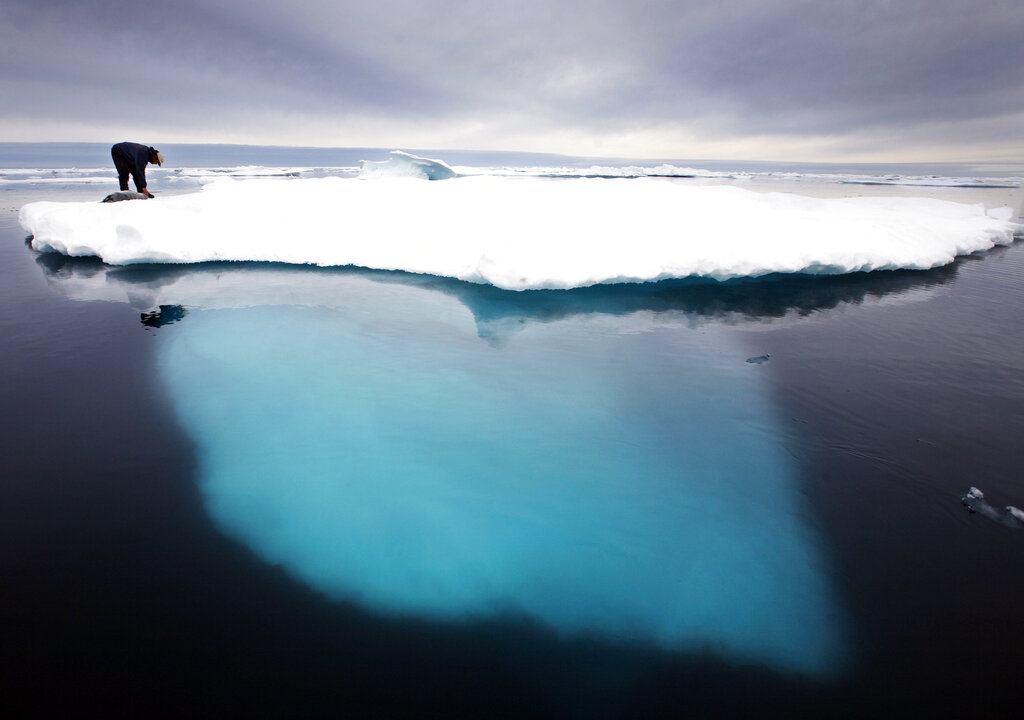 In this file photo dated July 2007, an Inuit seal hunter touches a dead seal atop a melting iceberg near Ammassalik Island, Greenland. (AP Photo/John McConnico, FILE)