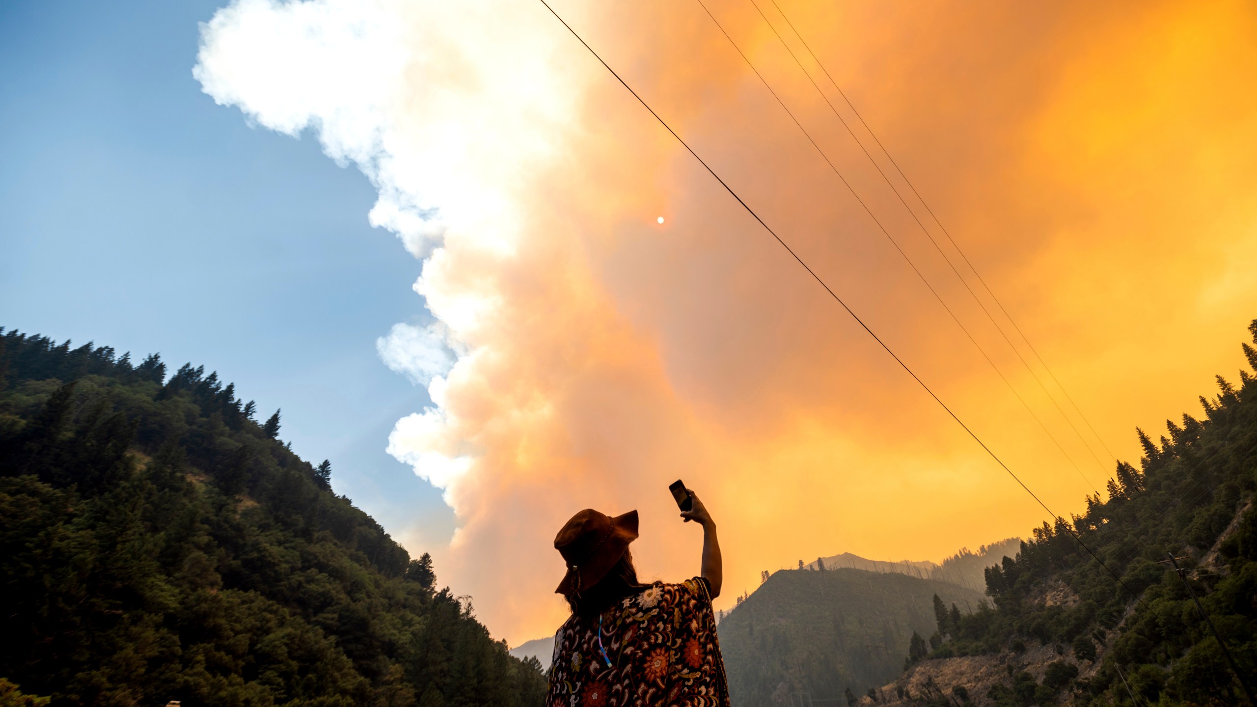 Jessica Bell takes a video as the Dixie Fire burns along Highway 70 in Plumas National Forest, Calif., on July 16, 2021. (AP Photo/Noah Berger)