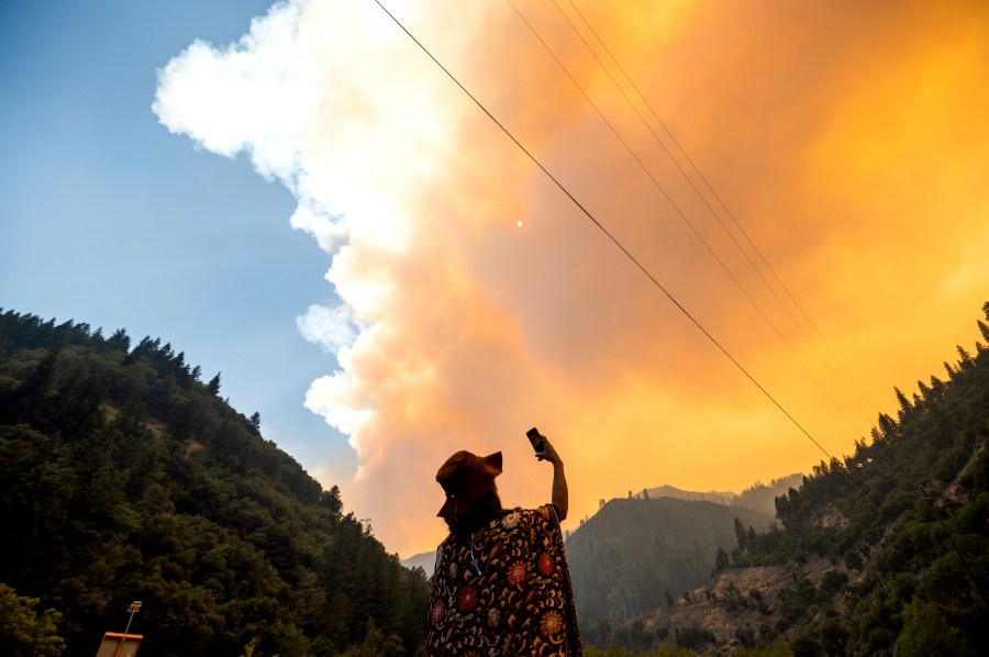 Jessica Bell takes a video as the Dixie Fire burns along Highway 70 in Plumas National Forest, Calif., on July 16, 2021. (AP Photo/Noah Berger)