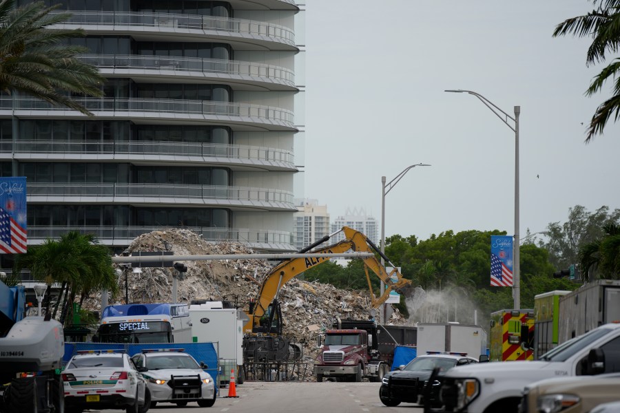 In this July 12, 2021 file photo, an excavator removes the rubble of the demolished section of the Champlain Towers South building, as recovery work continues at the site of the partially collapsed condo building, in Surfside, Fla. Another victim has been identified in the collapse of a 12-story Florida condominium. The Miami-Dade Police Department said in a news release Saturday, July 17, that Theresa Velasquez, 36, was a confirmed fatality in the June 24 collapse of the Champlain Towers South condo. (AP Photo/Rebecca Blackwell, File)