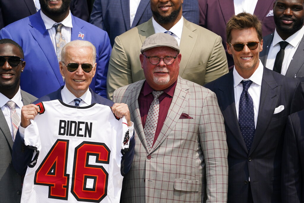 President Joe Biden, surrounded by members of the Tampa Bay Buccaneers, poses for a photo holding a jersey during a ceremony on the South Lawn of the White House, in Washington, Tuesday, July 20, 2021. (AP Photo/Andrew Harnik)